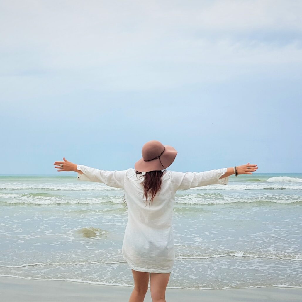 woman at beach with arms outstretched in freedom