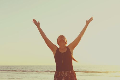 Woman on the beach with her arms up
